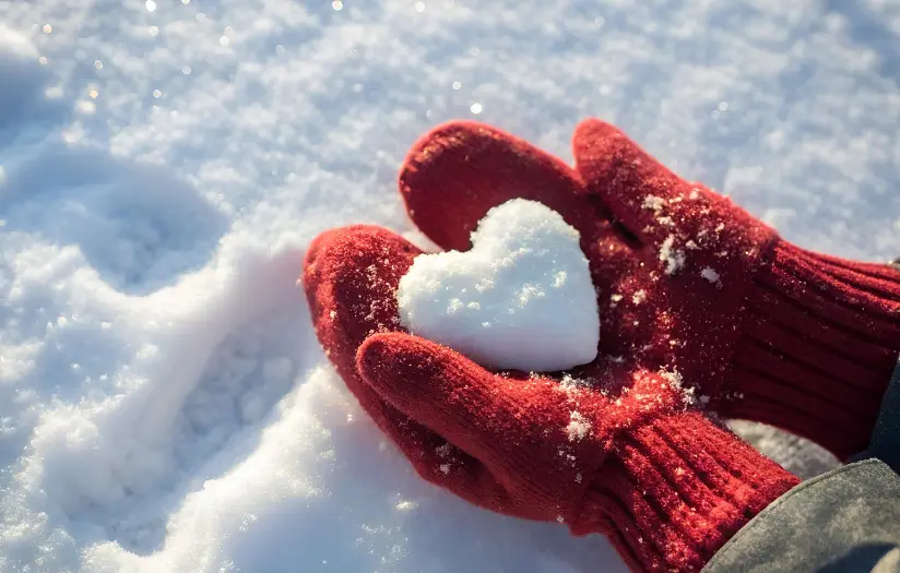 red-gloves-holding-a-snow-covered-heart-shaped-ornament-on-winter-landscape,-ideal-for-promoting-snow-flocking-powder-in-holiday-decorations-and-seasonal-crafts