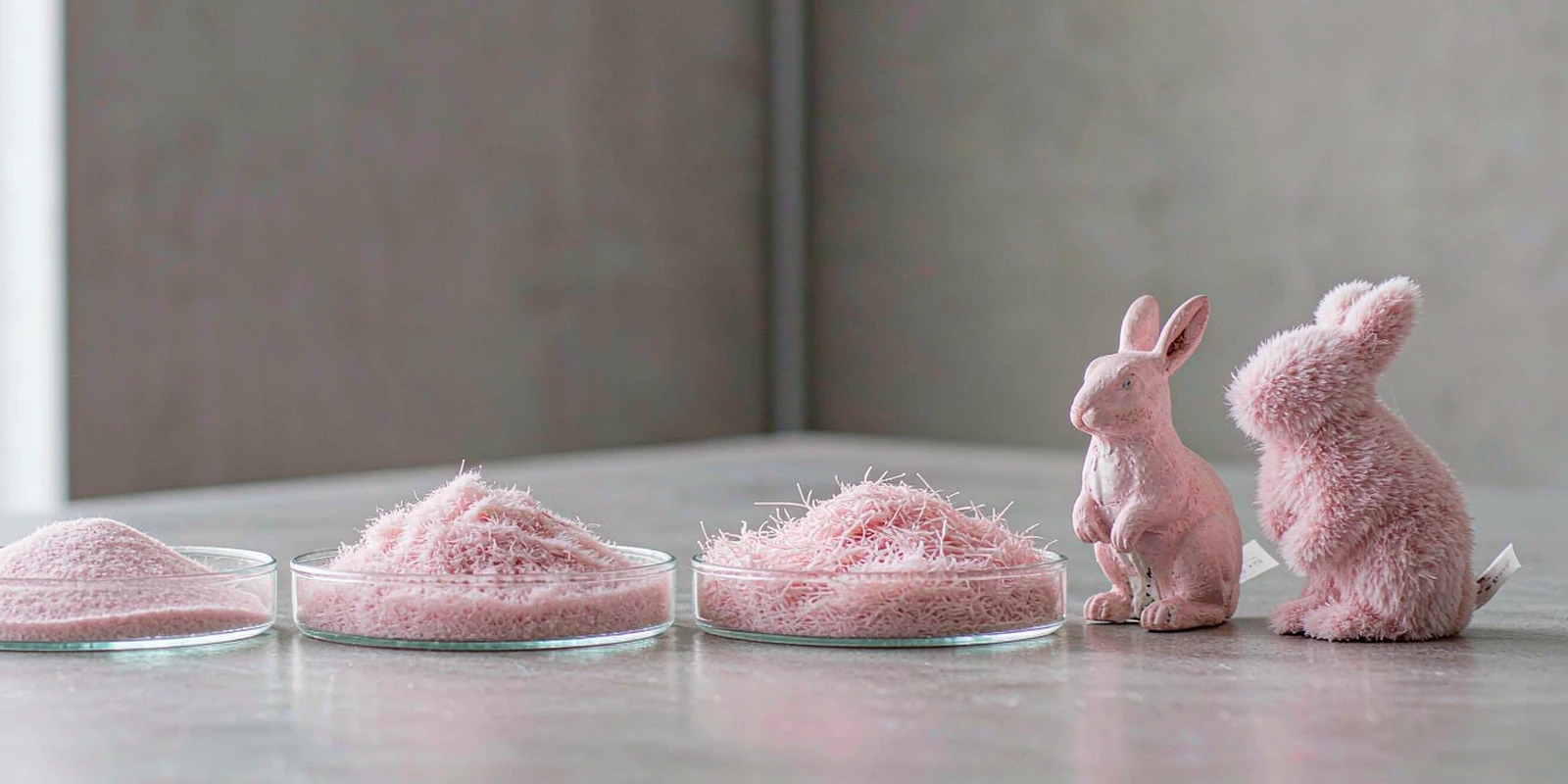 Trays of pink flocking fibre in different cut lengths with short and long pile flocked toy rabbit figurines Trays of pink flocking fibre in different cut lengths with short and long pile flocked toy rabbit figurines